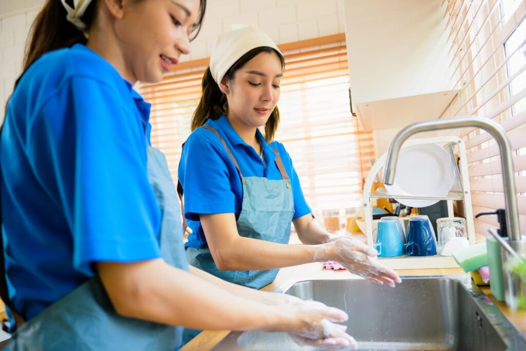 Two cleaning professionals taking care of a kitchen